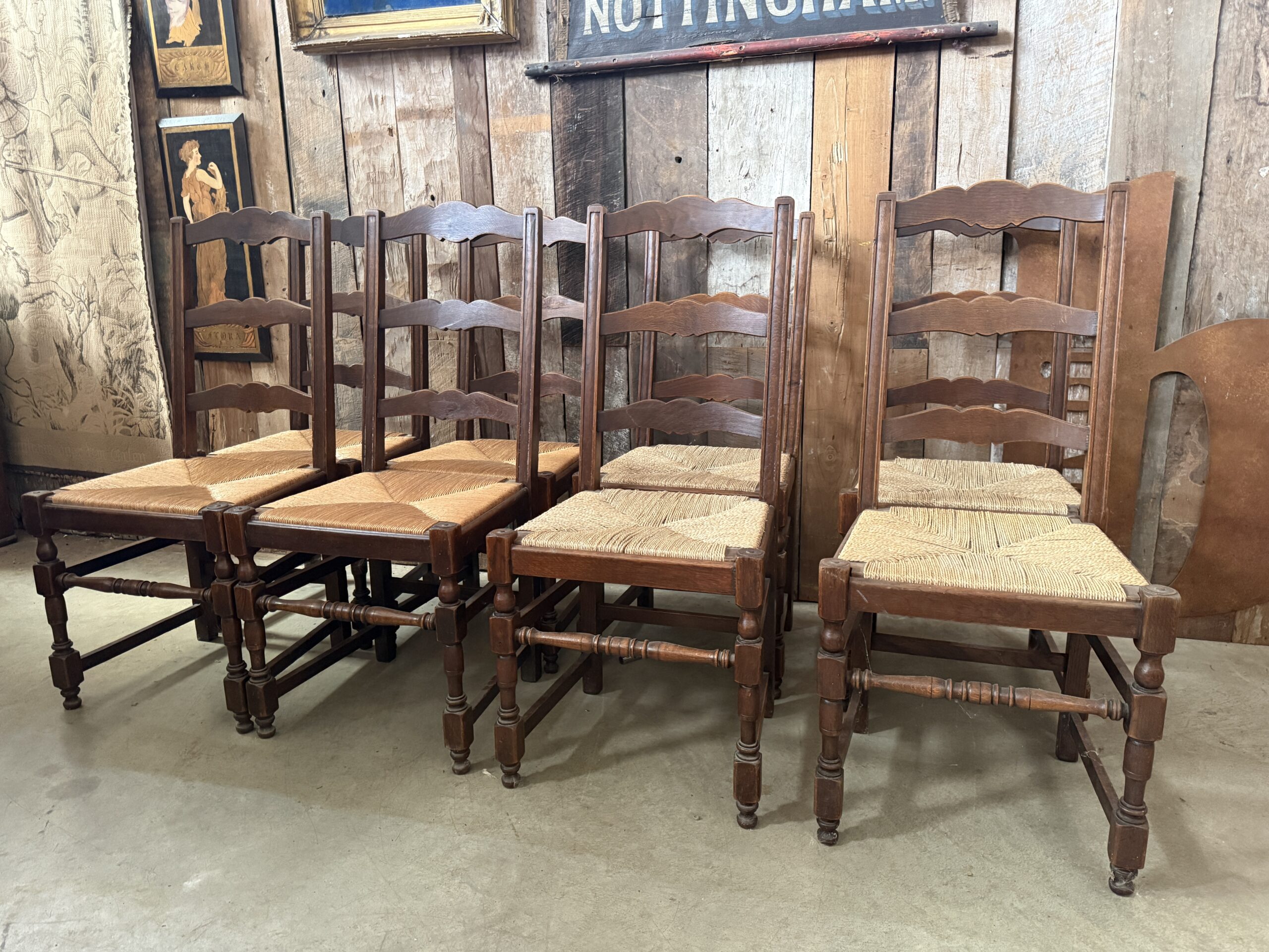 Set of eight vintage oak ladderback dining chairs with natural rush seats and turned legs.